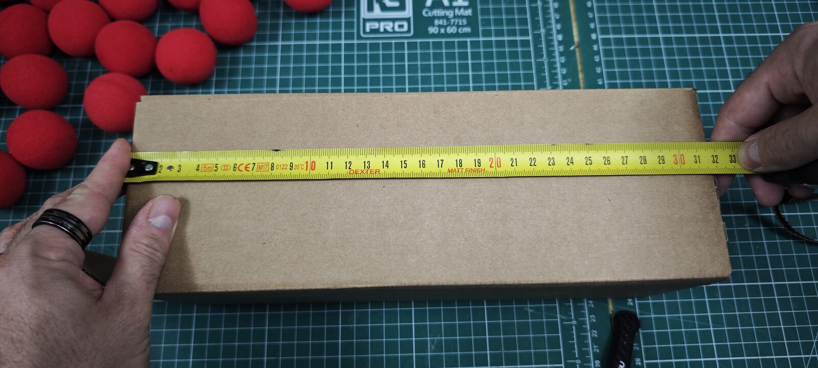 Mesure de la longueur du carton au mètre ruban : environ 32 cm
