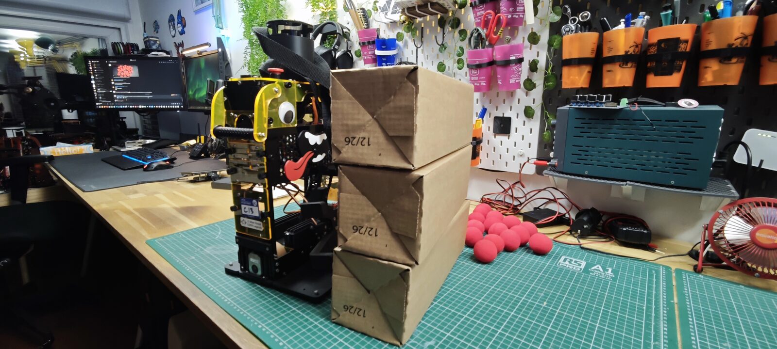 Trois cartons empilés à côté du robot de l'année dernière, vue de trois quarts