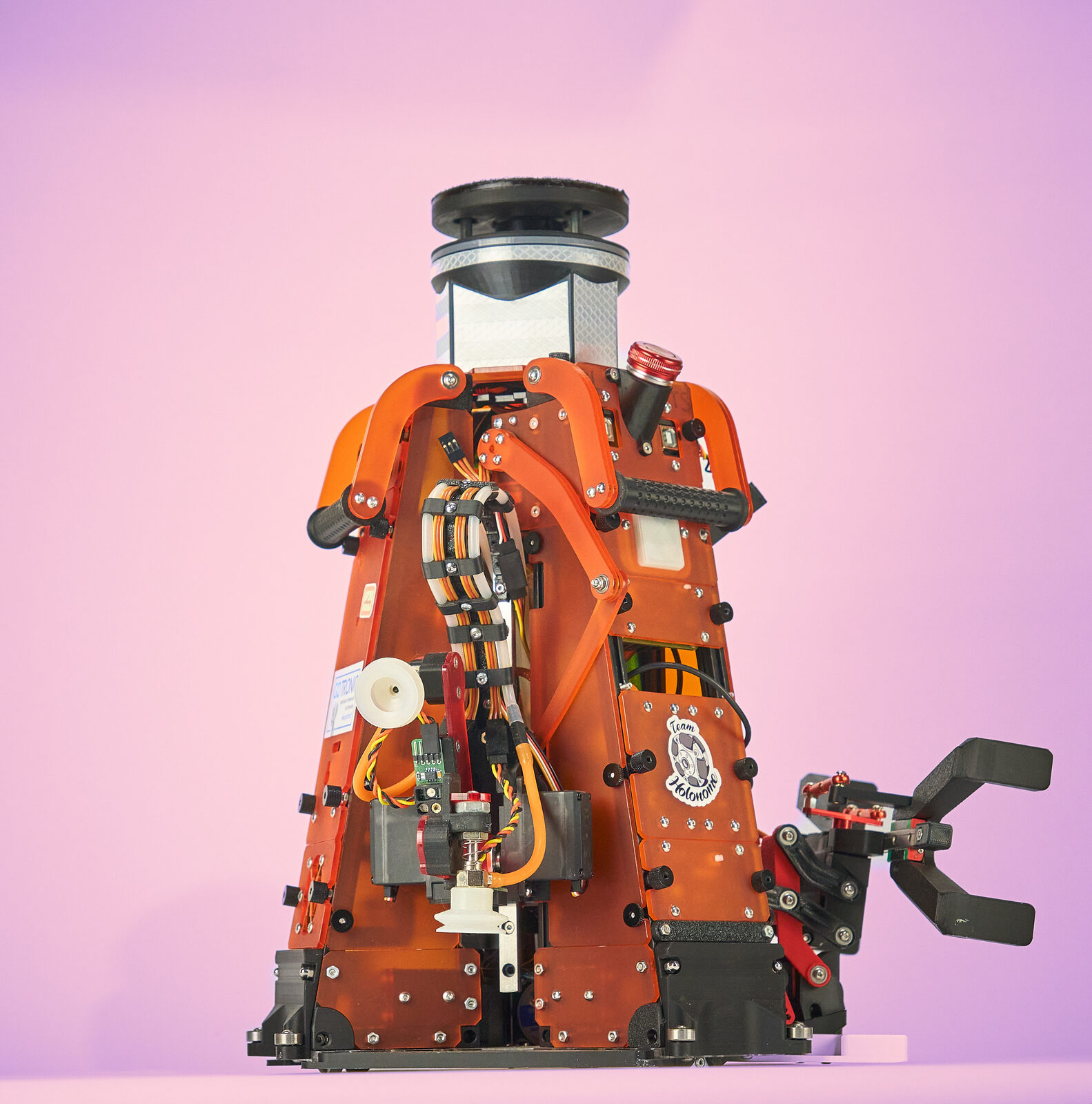Robot holonome orange vu de trois quarts, ventouses et pince visibles
